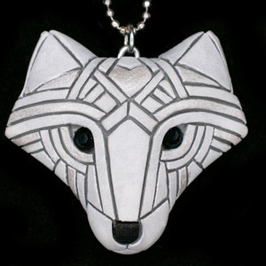 Photo shows a white Arctic fox necklace made in mosaic style from the front. Pendant hangs from a silver chain. Eyes are sparkling black crystals. Fits in the palm of your hand. Made to look like an ancient amulet.