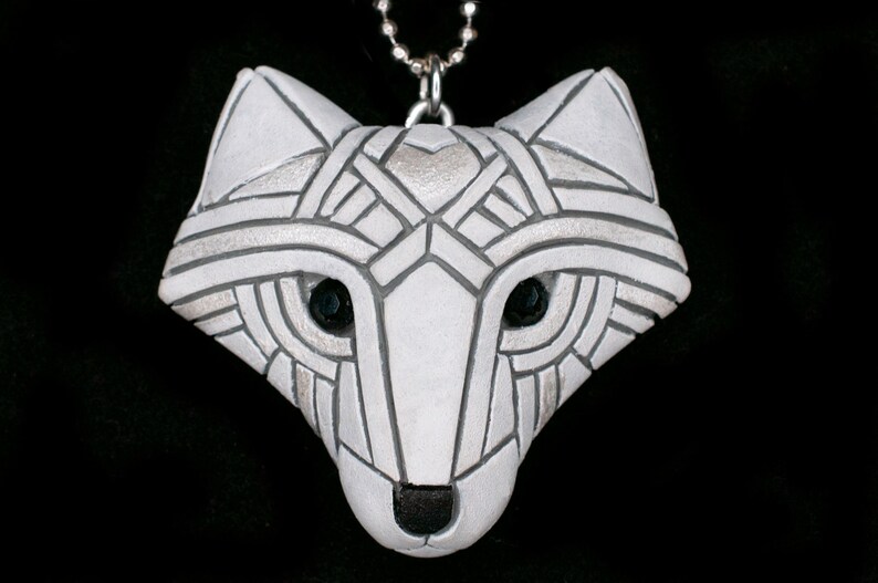 Photo shows a white Arctic fox necklace made in mosaic style from the front. Pendant hangs from a silver chain. Eyes are sparkling black crystals. Fits in the palm of your hand. Made to look like an ancient amulet.
