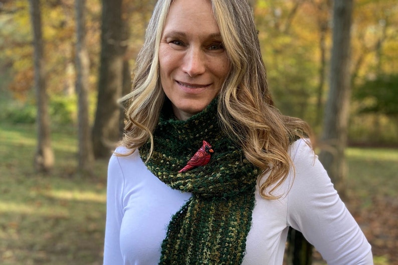 Photo shows model wearing bright red male cardinal on a scarf in an outdoor setting.