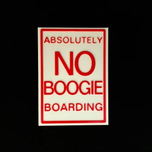 May include: A rectangular sign with a white background and a red border. The sign reads "ABSOLUTELY NO BOOGIE BOARDING" in bold red letters. The sign is likely used to indicate a restriction or prohibition.