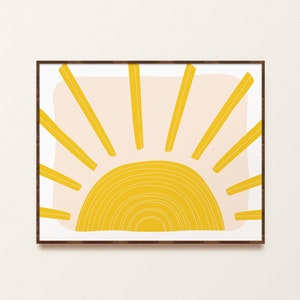 May include: A framed print of a stylised yellow sun with a pink background. The sun has a series of concentric circles and rays emanating from the centre.