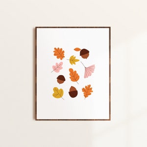 Puede incluir: Una impresión enmarcada con un fondo blanco y un patrón de bellotas marrones y hojas naranjas, rosas y amarillas.