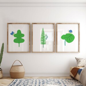 May include: Three framed illustrations of nature scenes. The first shows a green leaf with a blue butterfly. The second shows a green fern with a blue caterpillar. The third shows a green leaf with a blue snail.
