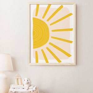 May include: A framed print of a stylised sun with yellow rays and a peach background.