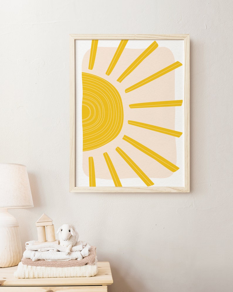 May include: A framed print of a stylised sun with yellow rays and a peach background.