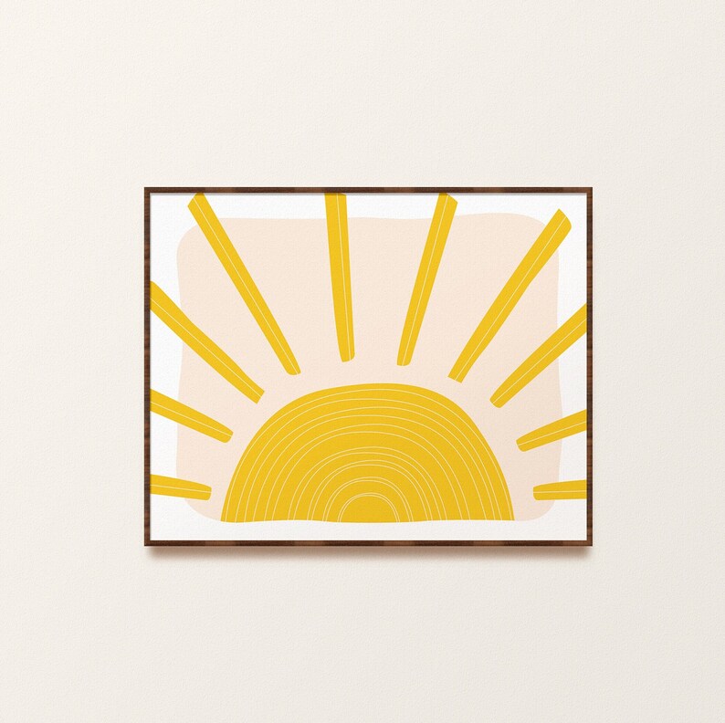 May include: A framed print of a stylised yellow sun with a pink background. The sun has a series of concentric circles and rays emanating from the centre.