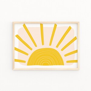 May include: A framed print of a stylised sun with yellow rays and a yellow and white arc on a pink background.