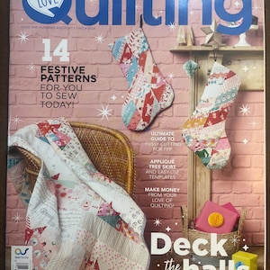 May include: The cover of "Patchwork & Quilting" magazine showcases a festive theme with Christmas stockings and a quilt. Text includes "14 Festive Patterns" and "Deck the Halls". The colour scheme features red, pink, and white, evoking a seasonal feel.