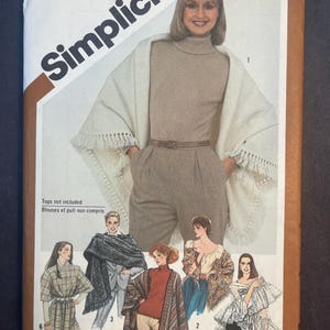 May include: A vintage Simplicity sewing pattern envelope. The cover features a woman wearing a beige turtleneck and pants, draped with a cream-colored shawl. The envelope includes illustrations of various tops and the text "Simplicity" and "5210".