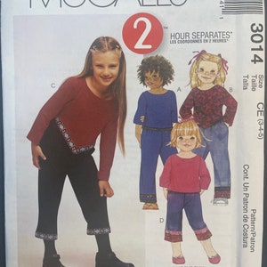 May include: McCall's sewing pattern number 3014 for children's clothing. The pattern includes instructions for making a red, blue, and purple top with a black, blue, or purple pair of trousers. The pattern is for sizes 3, 4, and 5.