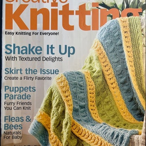 May include: A magazine cover for Creative Knitting magazine, featuring a knitted throw blanket in shades of yellow, green, and blue. The cover text reads "Shake It Up with Textured Delights", "Skirt the Issue Create a Flirty Favorite", "Puppets Parade Furry Friends You Can Knit", "Fleas & Bees Naturals For Baby", and "Breezy Ruffles Throw page 56 £6.99".