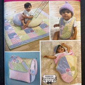 Puede incluir: Un patrón de costura para una colcha, una bolsa de pañales, un babero y una manta con capucha para bebé. El patrón es de Simplicity y es para una talla. El patrón incluye una variedad de colores y patrones, incluyendo rosa, azul, verde y amarillo.