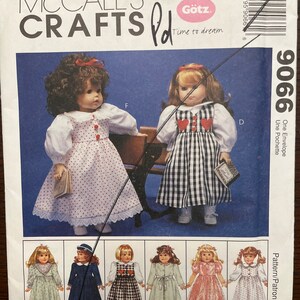 May include: A sewing pattern for making doll clothes. The pattern is for a doll that is about 18 inches tall. The pattern includes instructions for making a variety of dresses, including a white dress with red hearts, a black and white gingham dress, and a pink dress with white polka dots. The pattern also includes instructions for making a blue dress with white trim, a green dress with white trim, and a white dress with red trim. The pattern is from McCall's Crafts and is for Götz dolls. The pattern number is 9066.