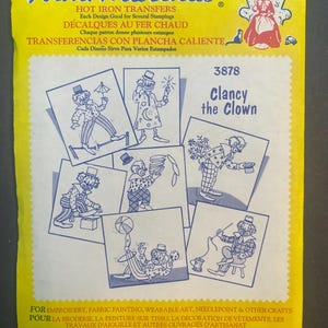Peut inclure: Feuille de transfert thermocollante avec six images différentes d'un clown nommé Clancy. La feuille est jaune avec du texte bleu et une bordure. Le texte indique "Aunt Martha's Hot Iron Transfers, Each Design Good for Several Stampings, Décalques Au Fer Chaud, Chaque patron donne plusieurs estampes, Transferencias Con Plancha Caliente, Cada Diseño Sirve Para Varios Estampados, 3878, Clancy the Clown".
