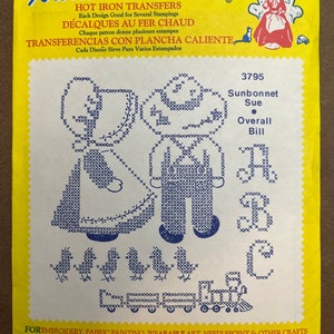 May include: A yellow and white iron-on transfer sheet with a design of a girl and boy in overalls and a sunbonnet. The text on the sheet reads "Aunt Martha's Hot Iron Transfers, Each Design Good for Several Stampings, Décalques Au Fer Chaud, Chaque patron donne plusieurs estampes, Transferencias Con Plancha Caliente, Cada Diseño Sirve Para Varios Estampados, 3795, Sunbonnet Sue, Overall Bill".