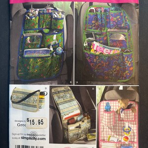May include: A sewing pattern for three different car seat organizers. The first organizer is green with a butterfly print and has multiple pockets. The second organizer is blue with a butterfly print and has multiple pockets. The third organizer is pink with a plaid print and has multiple pockets. The pattern is from Simplicity and is size one.