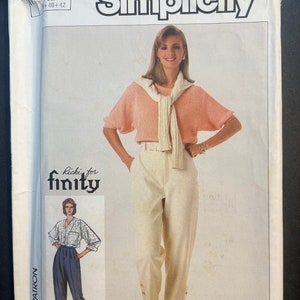 May include: Simplicity sewing pattern 7267 featuring a woman modeling a peach-colored short-sleeved sweater, cream-colored pants with button details, and a sweater draped over her shoulders. The pattern includes a smaller image of a different outfit. The pattern size is Eur +40+42.