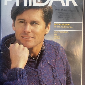 May include: Magazine cover featuring a man wearing a blue cable-knit sweater. The magazine title is "PHILDAR" in large white letters. Text includes "ROYAL FLUSH for the modern man" and "PHILDAR WOOLS".