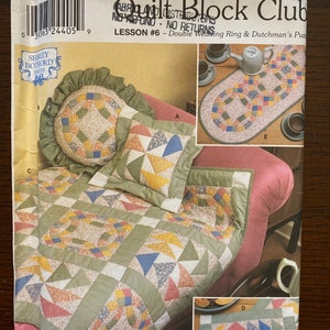 May include: Quilt Block Club Lesson #6 pattern featuring a double wedding ring and Dutchman's puzzle quilt block designs. The pattern includes instructions for making a quilt, cushion, and table runner.