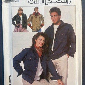 May include: A Simplicity sewing pattern for a denim jacket. The pattern includes three different views of the jacket, one with a red bandana, one with a white shirt, and one with a white shirt and a black leather jacket. The pattern is for size XS.