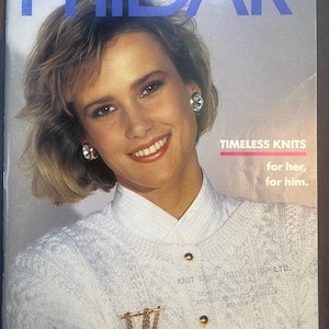 May include: Magazine cover showing a woman in a white knit sweater and collared shirt. The magazine title "PHIDAR" is in blue. Text reads "TIMELESS KNITS for her, for him." The cover also features a gold brooch and earrings.