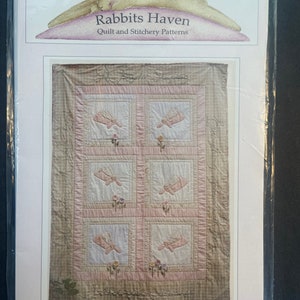 May include: A pink and brown quilt pattern with the title "Guardian Angels" and the text "Rabbits Haven Quilt and Stitchery Patterns".