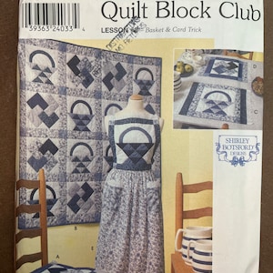 May include: A Simplicity Quilt Block Club pattern featuring a blue and white quilt design with a basket motif. The pattern includes instructions for making a quilt, an apron, and a chair cushion. The pattern is titled "Lesson #3 - Basket & Card Trick".