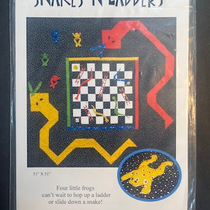 May include: A colorful Snakes and Ladders quilt pattern featuring a black and white checkerboard game board with red and yellow snakes and ladders. The pattern includes four frogs, a Canadian flag, and the text "Snakes 'N Ladders" and "Wanda's Designs".