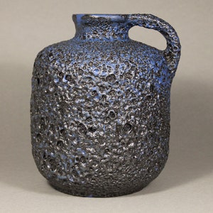 Könnte beinhalten: Eine blaue und schwarze Keramikvase mit einer strukturierten Oberfläche und einem Henkel. Die Vase hat einen runden Körper und einen schmalen Hals.