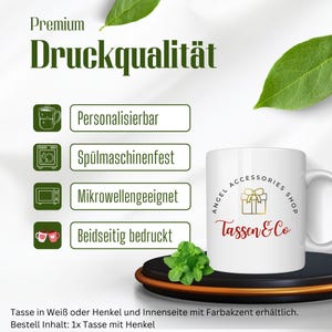 May include: White ceramic mug with a red and gold gift box design and the text "Angel Accessories Shop Tassen & Co". The mug is dishwasher, microwave, and personalisation safe. The mug is shown on a wooden coaster with a sprig of mint.
