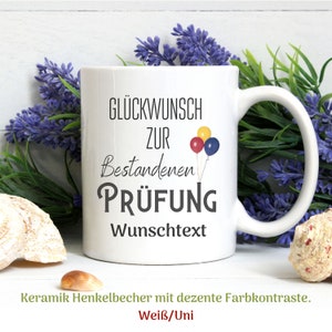 Könnte beinhalten: Weiße Keramiktasse mit schwarzem Henkel. Die Tasse hat eine schwarze Grafik mit der Aufschrift "Glückwunsch zur bestandenen Prüfung" mit drei bunten Luftballons. Der Text "Wunschtext" befindet sich unter der Grafik.