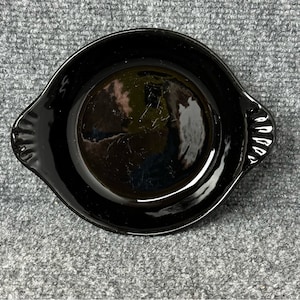 May include: A black ceramic baking dish with two handles. The dish is round and has a glossy finish.