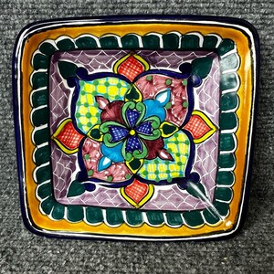 May include: Square ceramic serving dish with a colorful floral design. The dish features a central flower motif in blue, green, yellow, red, and purple, surrounded by a patterned border. The rim is outlined in blue and yellow.