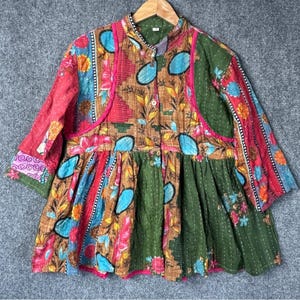 May include: A colorful patchwork jacket with a mandarin collar and button-down front. The jacket features a mix of floral and geometric patterns in shades of red, green, blue, and brown. The sleeves are three-quarter length, and the jacket has a ruffled hem.