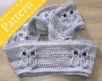 May include: Grey and white crocheted owl scarf with black button eyes. The scarf is made in a textured stitch and has a fringe at the ends. The scarf is folded in half and the ends are tucked inside.