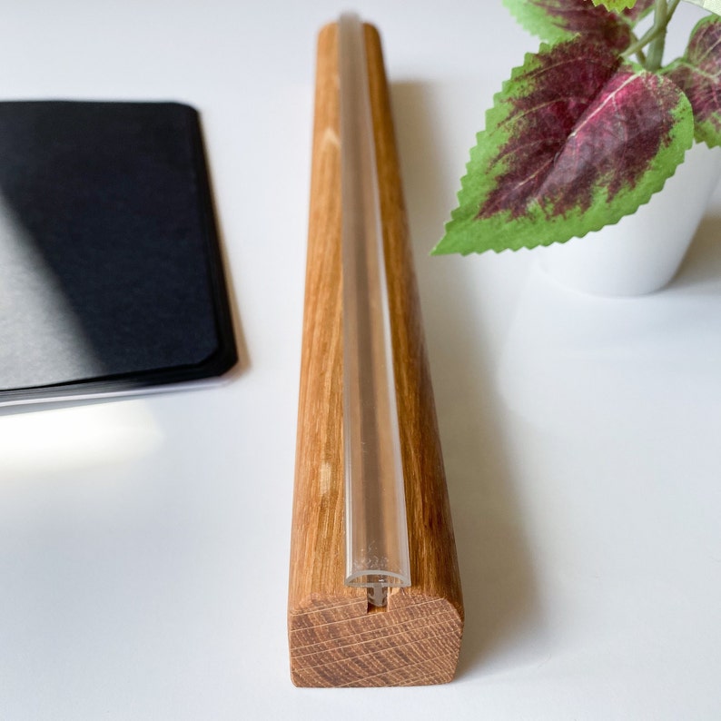 May include: A wooden stand with a clear glass tube running through it. The stand is made of light brown wood and has a natural finish.