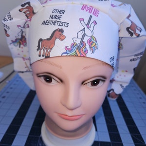 K&ouml;nnte beinhalten: Eine wei&szlig;e OP-M&uuml;tze mit einem Einhorn- und Pferde-Design. Die M&uuml;tze tr&auml;gt den Text "Ich" und "Andere Krankenschwestern An&auml;sthesisten".
