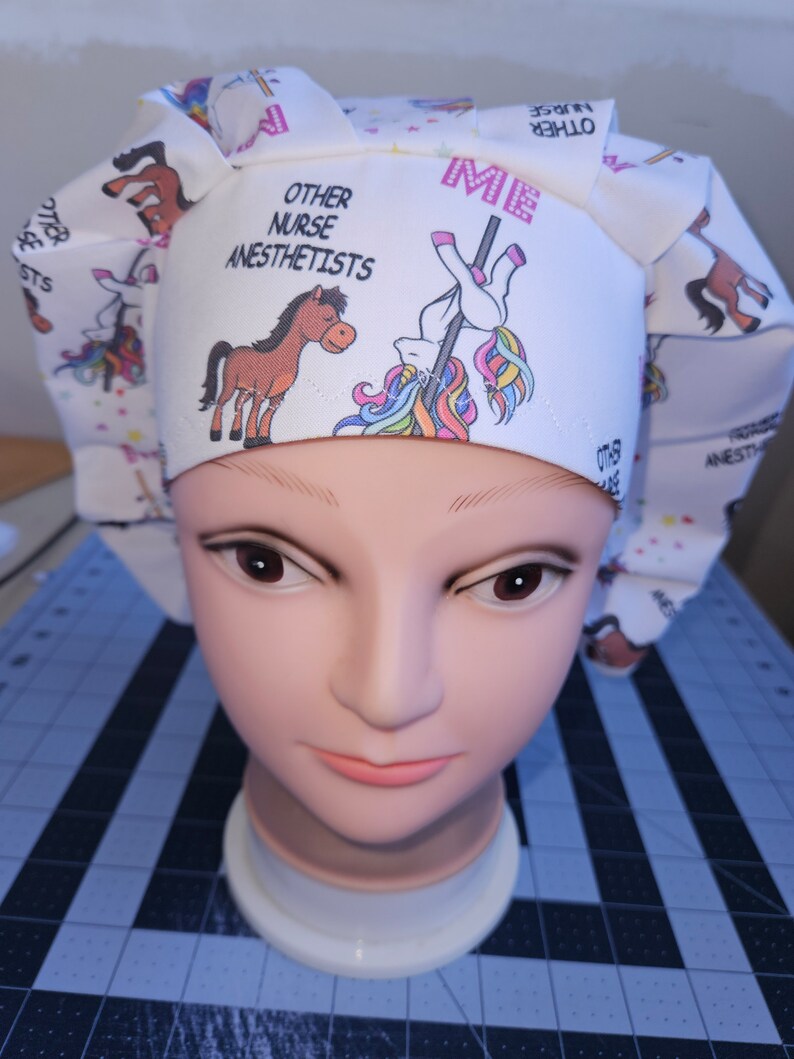 K&ouml;nnte beinhalten: Eine wei&szlig;e OP-M&uuml;tze mit einem Einhorn- und Pferde-Design. Die M&uuml;tze tr&auml;gt den Text "Ich" und "Andere Krankenschwestern An&auml;sthesisten".