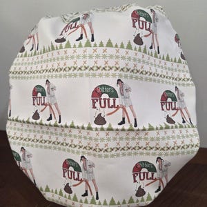 May include: A white scrub cap featuring a repeating pattern of a person in a bathrobe holding a hose with the text Shitter's FULL above a brown pile. The design includes horizontal bands of green pine trees and small red berries on a white background.