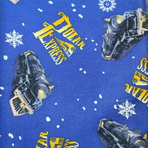 May include: Blue fabric with a repeating pattern of a train engine, snowflakes, and the words "Polar Express".