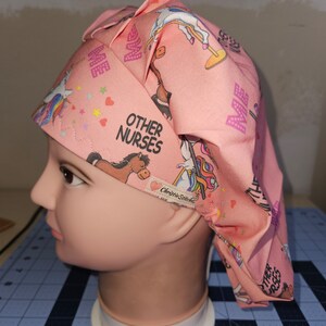 K&ouml;nnte beinhalten: Rosa chirurgische M&uuml;tze mit einem Einhorn- und Pferde-Druck. Die M&uuml;tze hat den Text "Other Nurses" und "Me" aufgedruckt. Die M&uuml;tze befindet sich auf einem wei&szlig;en Mannequin-Kopf.