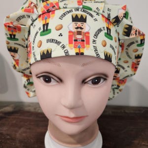 May include: A green and white scrub hat with a repeating pattern of nutcrackers and the text "Everyday I'm crushing it".