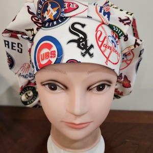 May include: White scrub hat with a colorful pattern of various baseball team logos, including the New York Yankees, Chicago Cubs, and Boston Red Sox.