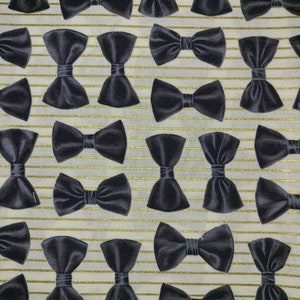 May include: A white fabric with gold stripes and a repeating pattern of black bow ties.