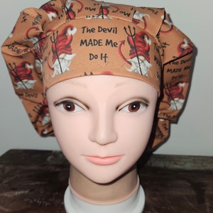 May include: A brown scrub cap featuring a repeating pattern of devil gnomes with pitchforks and the text "The Devil MADE Me Do It." The cap is designed to cover the hair and is likely for medical or culinary use.