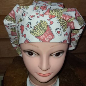 May include: White scrub hat with a print of french fries and hearts. The text on the hat reads "Fries Before Guys".