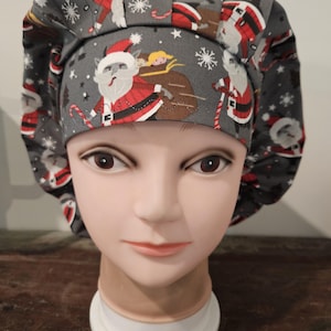 May include: A gray and white scrub hat with a Christmas theme featuring Santa Claus and snowflakes.