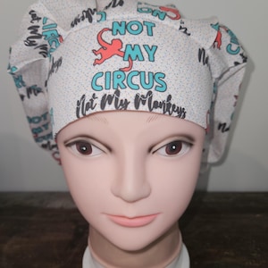 May include: White scrub hat with a red monkey and the text "Not My Circus, Not My Monkeys" in black and teal.