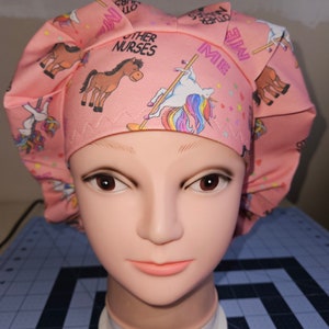 K&ouml;nnte beinhalten: Rosa chirurgische M&uuml;tze mit einem Einhorn-, Pferde- und Sternenmuster. Die M&uuml;tze tr&auml;gt den Text "Other Nurses" und "Me".