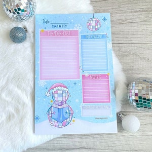 May include: A blue and pink printable planner with a snowman illustration. The planner has sections for to-do lists, important notes, and a highlight of the day. The planner also includes a date section with the days of the week abbreviated.